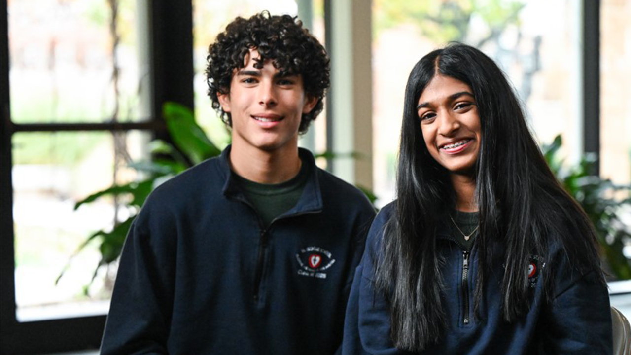 Portrait of a you man on the left with dark curly hair and a young lady on the right with braces and long dark hair.